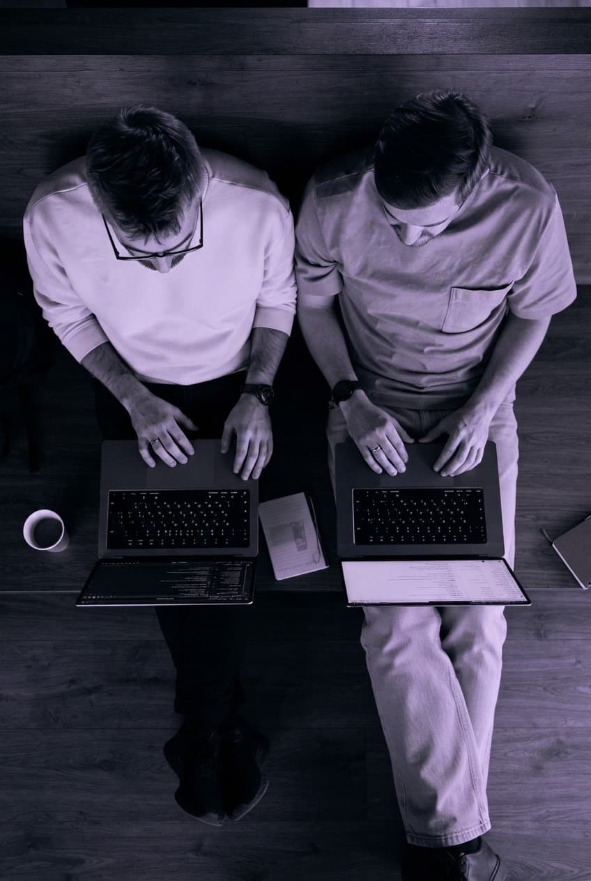 Die beiden Gründer von CIRO Effort arbeiten nebeneinander an ihren Laptops, von oben fotografiert